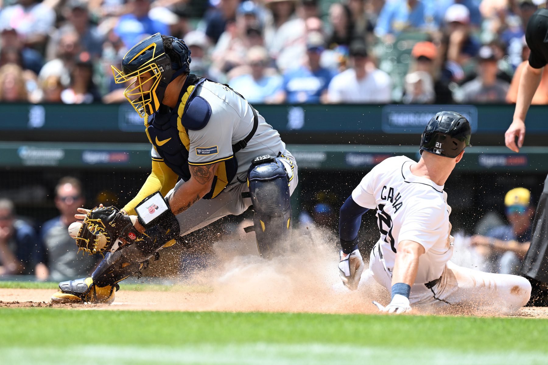 Jun 9, 2024; Detroit, Michigan, USA; Detroit Tigers designated hitter Mark Canha (21) slides safely into home plate ahead of the throw to Milwaukee Brewers catcher Gary Sánchez (99) in the first inning at Comerica Park. Mandatory Credit: Lon Horwedel-Imagn Images