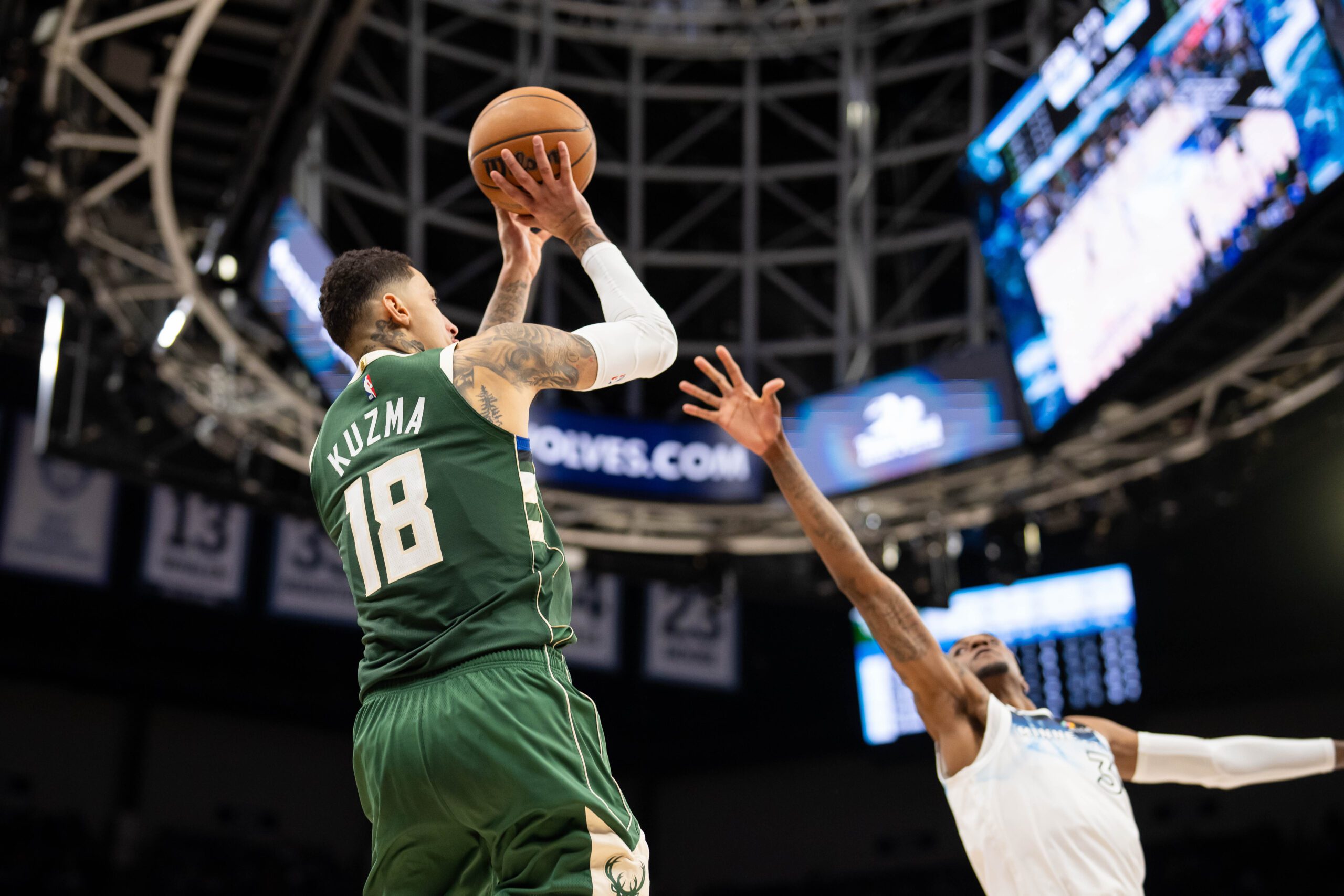 Feb 12, 2025; Minneapolis, Minnesota, USA; Milwaukee Bucks forward Kyle Kuzma (18) shoots against Minnesota Timberwolves forward Jaden McDaniels (3) in the fourth quarter at Target Center. Mandatory Credit: Brad Rempel-Imagn Images