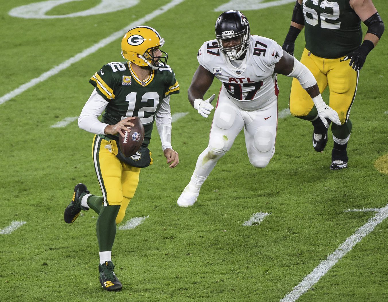 Oct 5, 2020; Green Bay, Wisconsin, USA; Green Bay Packers quarterback Aaron Rodgers (12) scrambles away from Atlanta Falcons defensive tackle Grady Jarrett (97) in the second quarter at Lambeau Field. Mandatory Credit: Benny Sieu-Imagn Images