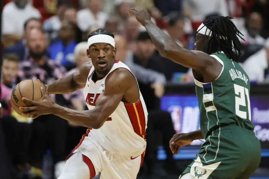 Apr 22, 2023; Miami, Florida, USA; Miami Heat forward Jimmy Butler (22) drives to the basket against Milwaukee Bucks guard Jrue Holiday (21) in the first quarter during game three of the 2023 NBA Playoffs at Kaseya Center. Mandatory Credit: Sam Navarro-USA TODAY Sports (NBA News)