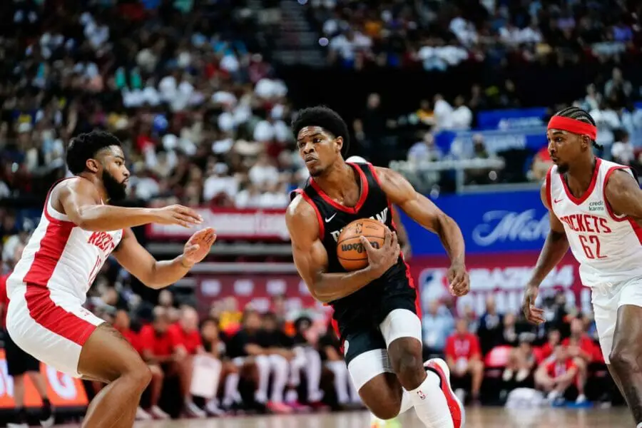 Jul 7, 2023; Las Vegas, NV, USA; Portland Trail Blazers guard Scoot Henderson (00) drives the ball against Houston Rockets guard Trevor Hudgins (12) and guard/forward Nate Hinton (62) during the first half at Thomas & Mack Center. Mandatory Credit: Lucas Peltier-USA TODAY Sports (NBA News)