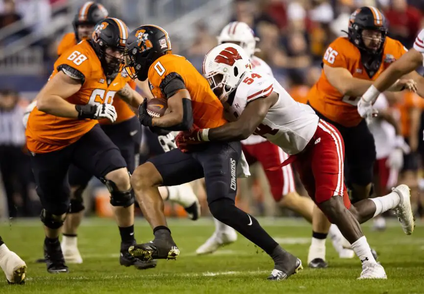 Dec 27, 2022; Phoenix, Arizona, USA; Oklahoma State Cowboys running back Ollie Gordon (0) is tackled by Wisconsin Badgers linebacker Jordan Turner (54) in the first half of the 2022 Guaranteed Rate Bowl at Chase Field. Mandatory Credit: Mark J. Rebilas-USA TODAY Sports (Luke Fickell)