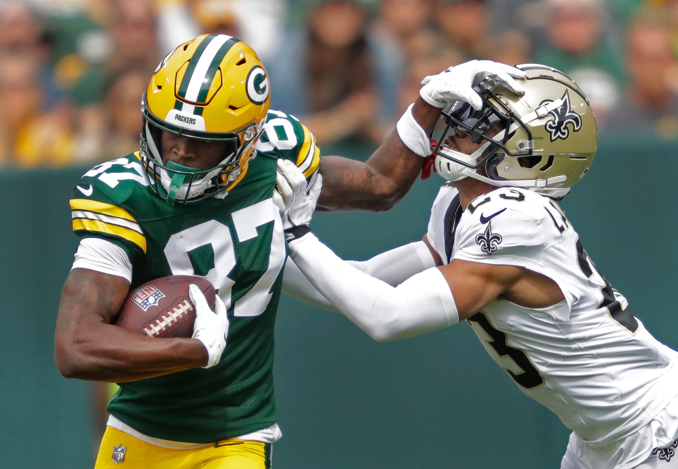 Green Bay Packers wide receiver Romeo Doubs (87) fends off New Orleans Saints cornerback Isaac Yiadom (27) during their football game Sunday, September 24, 2023, at Lambeau Field in Green Bay, Wis.