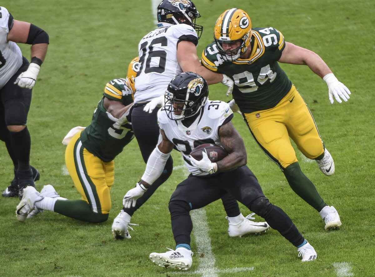 Nov 15, 2020; Green Bay, Wisconsin, USA; Jacksonville Jaguars running back James Robinson (30) runs against Green Bay Packers defensive end Dean Lowry (94) in the fourth quarter at Lambeau Field. Mandatory Credit: Benny Sieu-USA TODAY Sports