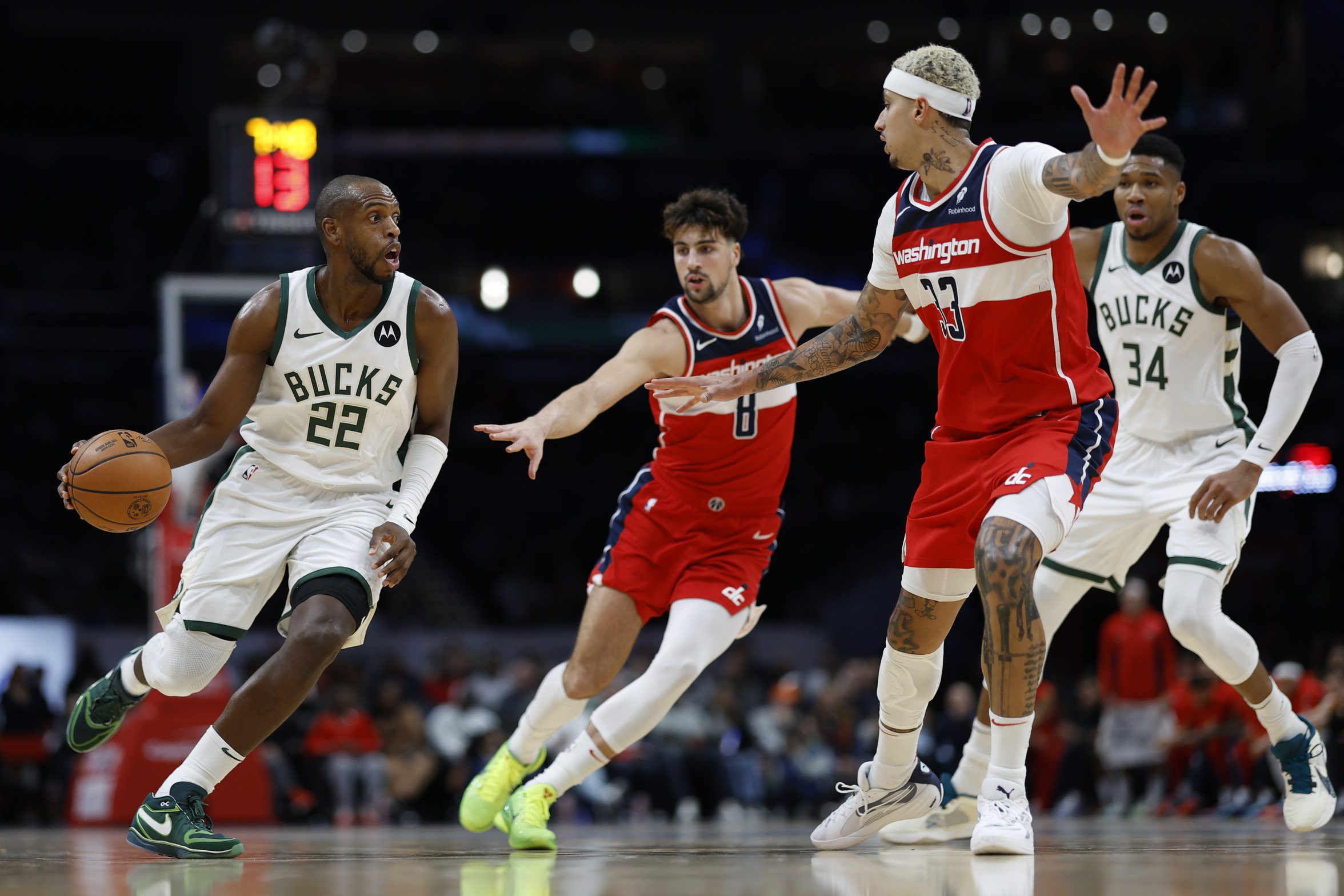 Nov 20, 2023; Washington, District of Columbia, USA; Milwaukee Bucks forward Khris Middleton (22) drives to the basket as Washington Wizards forward Deni Avdija (8) and Wizards forward Kyle Kuzma (33) defend in the fourth quarter at Capital One Arena. Mandatory Credit: Geoff Burke-USA TODAY Sports