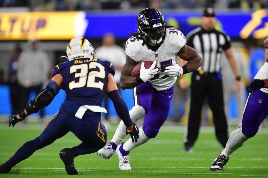 Nov 26, 2023; Inglewood, California, USA; Baltimore Ravens running back Gus Edwards (35) runs the ball against Los Angeles Chargers safety Alohi Gilman (32) during the first half at SoFi Stadium. Mandatory Credit: Gary A. Vasquez-USA TODAY Sports