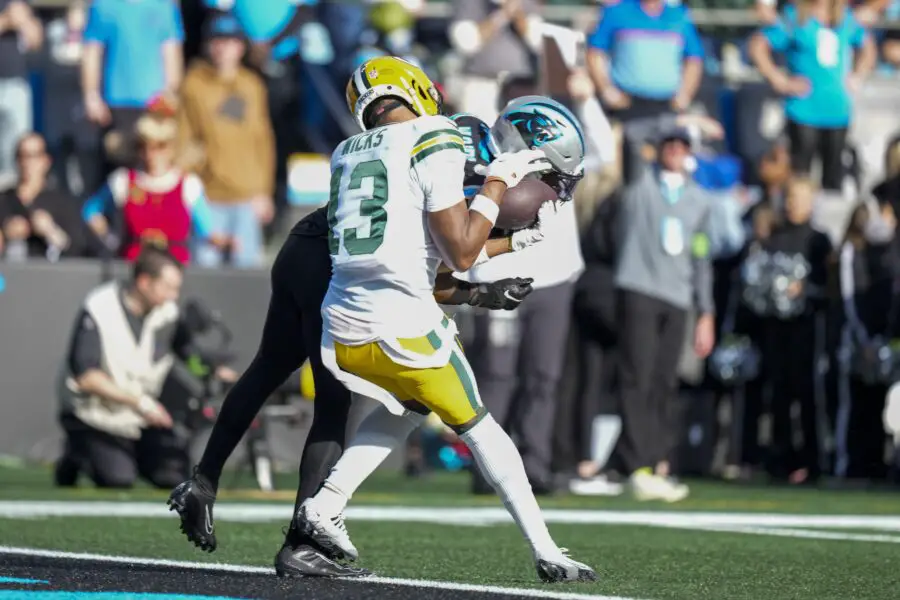 Dec 24, 2023; Charlotte, North Carolina, USA; Green Bay Packers wide receiver Dontayvion Wicks (13) makes a touchdown catch defended by Carolina Panthers safety Xavier Woods (25) during the second quarter at Bank of America Stadium. Mandatory Credit: Jim Dedmon-USA TODAY Sports