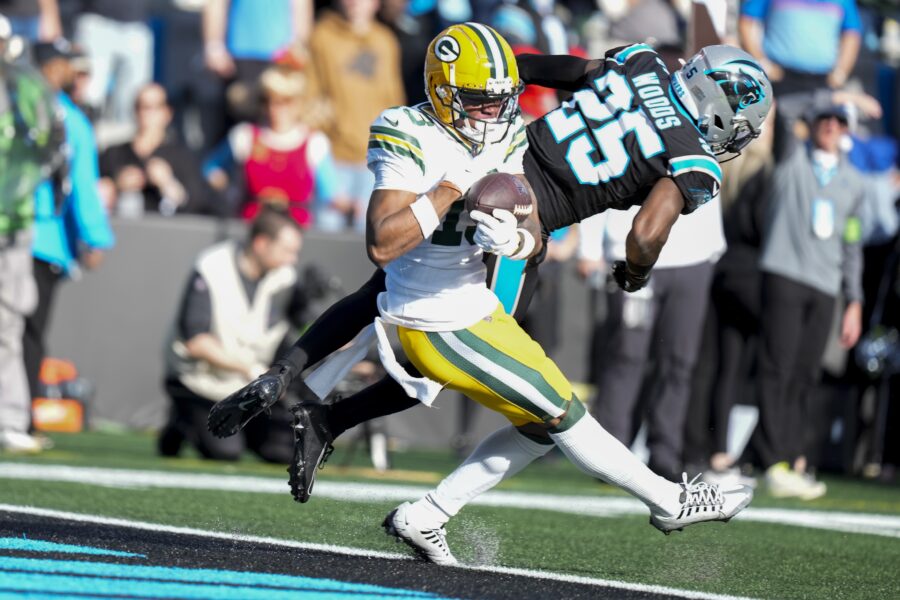 Dec 24, 2023; Charlotte, North Carolina, USA; Green Bay Packers wide receiver Dontayvion Wicks (13) makes a touchdown catch defended by Carolina Panthers safety Xavier Woods (25) during the second quarter at Bank of America Stadium. Mandatory Credit: Jim Dedmon-USA TODAY Sports
