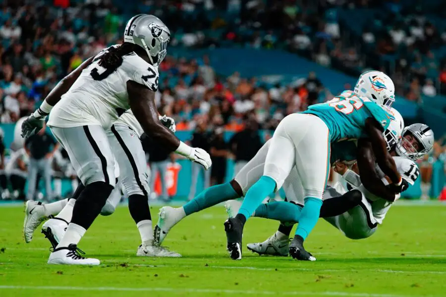 Aug 20, 2022; Miami Gardens, Florida, USA; Las Vegas Raiders quarterback Chase Garbers (15) is sacked by Miami Dolphins defensive tackle Owen Carney (93) and linebacker Deandre Johnson (56) during the second half at Hard Rock Stadium. Mandatory Credit: Rich Storry-USA TODAY Sports