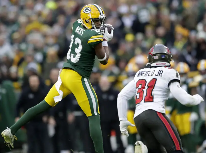 Dec 17, 2023; Green Bay, Wisconsin, USA; Green Bay Packers wide receiver Dontayvion Wicks (13) catches a pass in front of the defense of Tampa Bay Buccaneers safety Antoine Winfield Jr. (31) at Lambeau Field. Mandatory Credit: William Glasheen-USA TODAY Sports