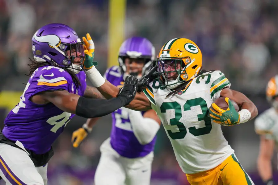 Dec 31, 2023; Minneapolis, Minnesota, USA; Green Bay Packers running back Aaron Jones (33) runs with the ball against the Minnesota Vikings safety Josh Metellus (44) in the first quarter at U.S. Bank Stadium. Mandatory Credit: Brad Rempel-USA TODAY Sports