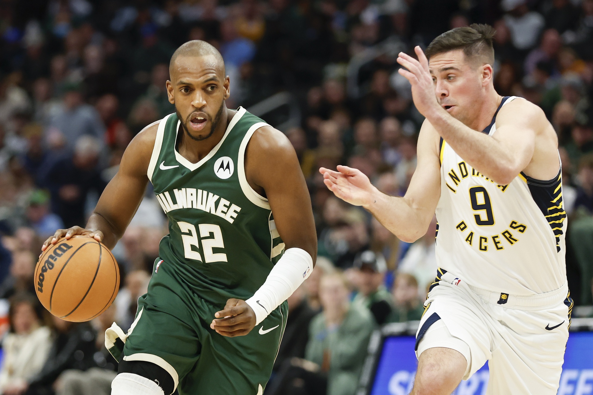 Jan 1, 2024; Milwaukee, Wisconsin, USA; Milwaukee Bucks forward Khris Middleton (22) drives to the basket against Indiana Pacers guard T.J. McConnell (9) during the first half at Fiserv Forum. Mandatory Credit: Kamil Krzaczynski-USA TODAY Sports