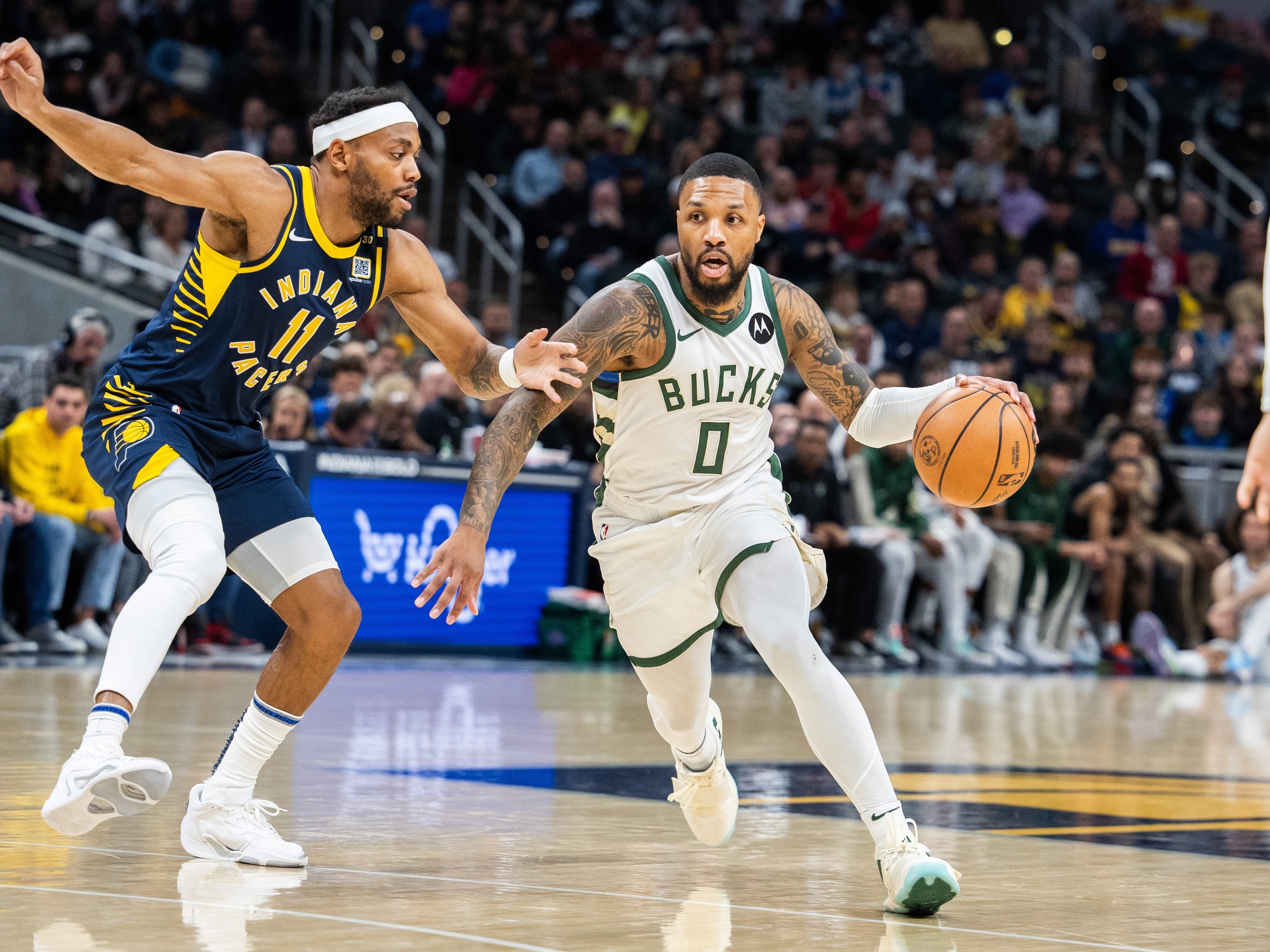 Jan 3, 2024; Indianapolis, Indiana, USA; Milwaukee Bucks guard Damian Lillard (0) dribbles the ball while Indiana Pacers forward Bruce Brown (11) defends in the first quarter at Gainbridge Fieldhouse. Mandatory Credit: Trevor Ruszkowski-USA TODAY Sports