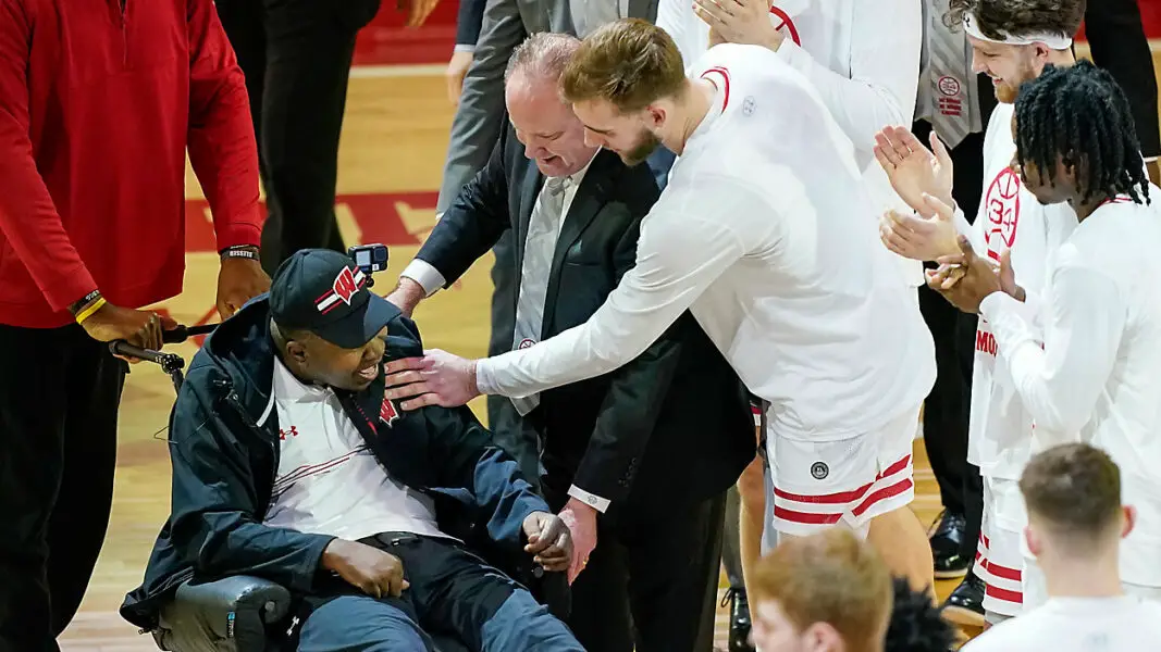 Former Wisconsin player and assistant coach Howard Moore is greeted by the Wisconsin team Saturday, March 2, 2024, in Madison, Wis., in in his first public appearance at the Kohl Center since a 2019 car wreck killed his wife and daughter and left him with serious injuries. (AP Photo/Andy Manis)