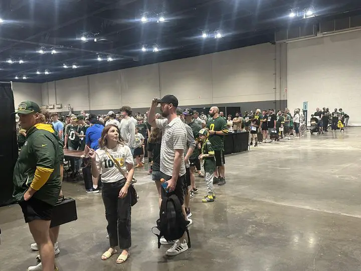 A large crowd of Green Bay Packers fans wait in line to take a photo with quarterback Jordan Love. 