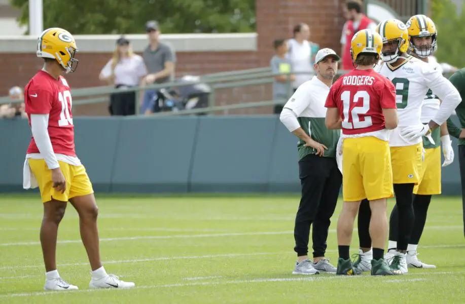 July 28, 2021; Green Bay, WI, USA; Green Bay Packers quarterback Jordan Love (10) looks on as quarterback Aaron Rodgers (12) talks with head coach Mike LeFleur and tight end Marcedes Lewis (89) during training camp Wednesday, July 28, 2021, in Green Bay, Wis. Mandatory Credit: Dan Powers-USA TODAY NETWORK