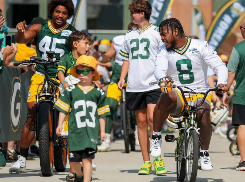 Green Bay Packers running back Josh Jacobs (8) talks with a young boy as he rides the boy's bicycle to practice in the Dream Drive during the first day of training camp on Monday, July 22, 2024, at Lambeau Field in Green Bay, Wis. Tork Mason/USA TODAY NETWORK-Wisconsin