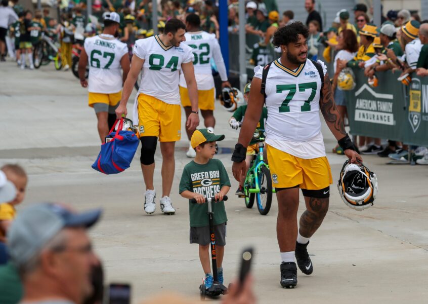 Green Bay Packers offensive lineman Jordan Morgan (77) walks with a young fan in the DreamDrive before practice on Tuesday, July 23, 2024, at Lambeau Field in Green Bay, Wis. Tork Mason/USA TODAY NETWORK-Wisconsin