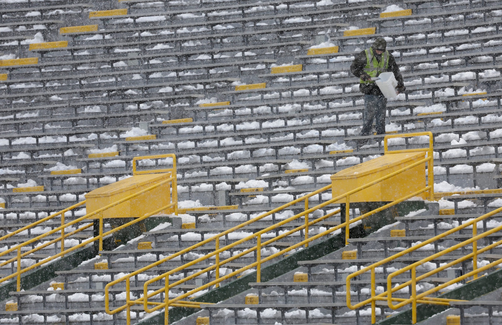 As snow falls, a worker spreads salt in the seating area of Lambeau Field prior to the Green Bay Packers playing against the Seattle Seahawks Sunday, November 14, 2021, at Lambeau Field in Green Bay, Wis. Dan Powers/USA TODAY NETWORK-Wisconsin