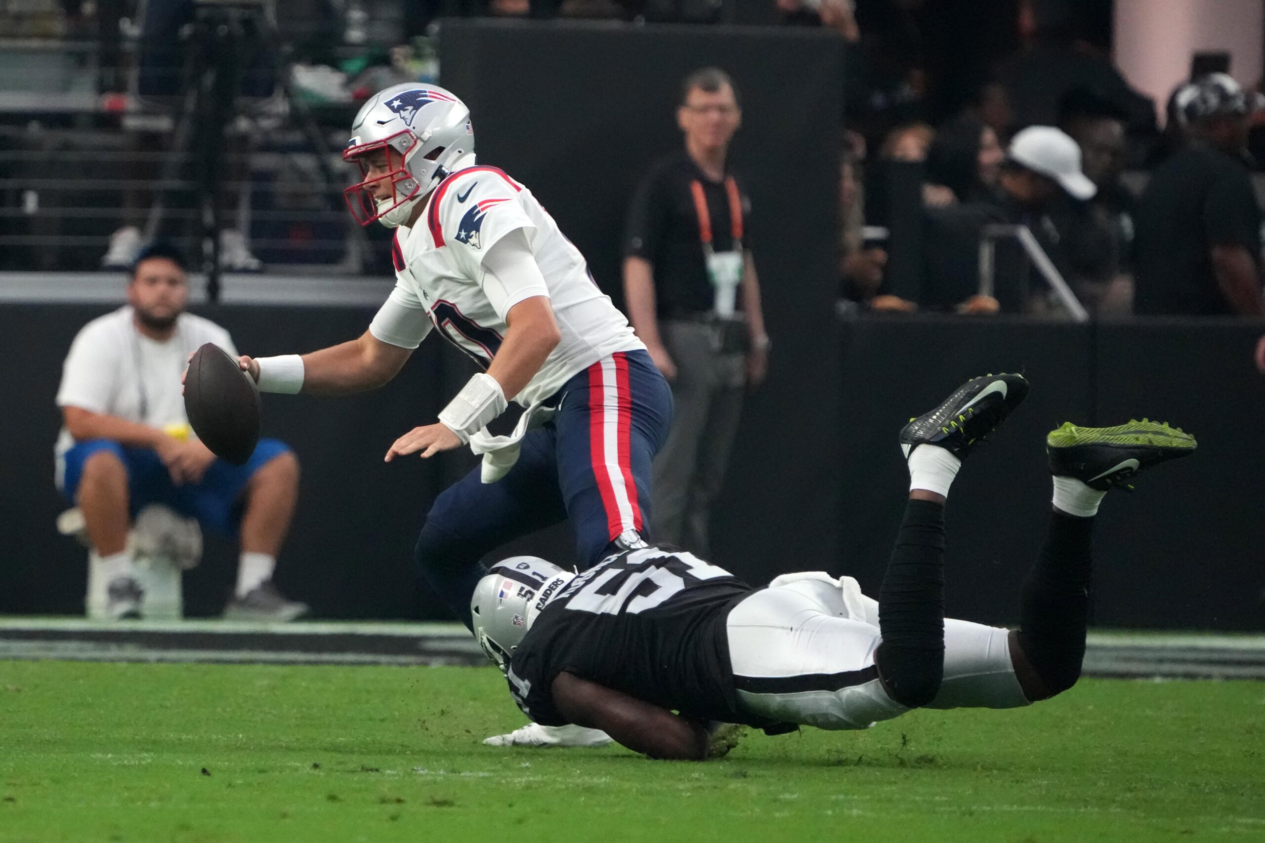 Aug 26, 2022; Paradise, Nevada, USA; New England Patriots quarterback Mac Jones (10) is tackled by Las Vegas Raiders defensive end Malcolm Koonce (51) in the first half at Allegiant Stadium. Mandatory Credit: Kirby Lee-Imagn Images