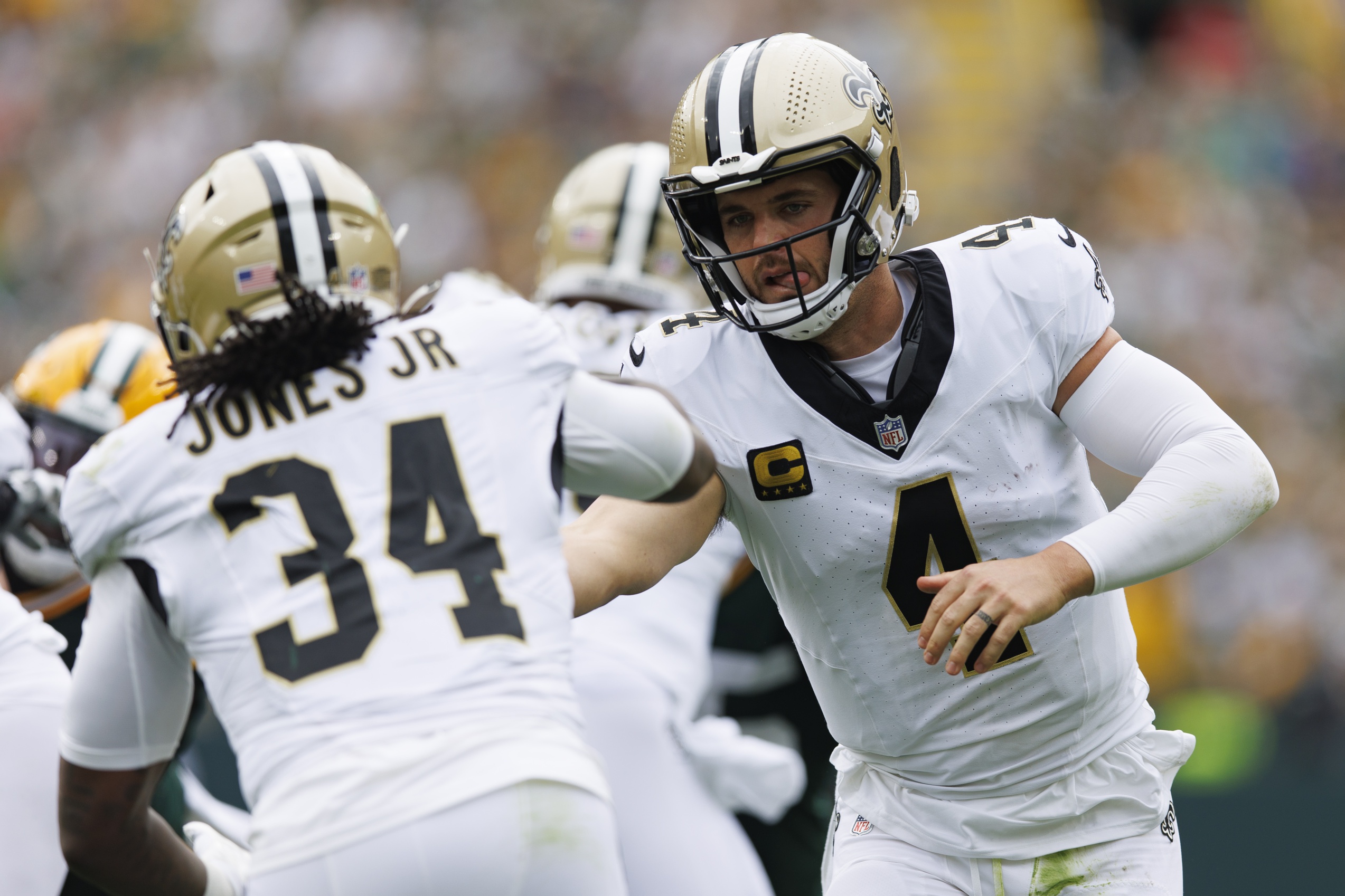 Sep 24, 2023; Green Bay, Wisconsin, USA; New Orleans Saints quarterback Derek Carr (4) hands the football off to running back Tony Jones Jr. (34) during the second quarter against the Green Bay Packers at Lambeau Field. Mandatory Credit: Jeff Hanisch-Imagn Images