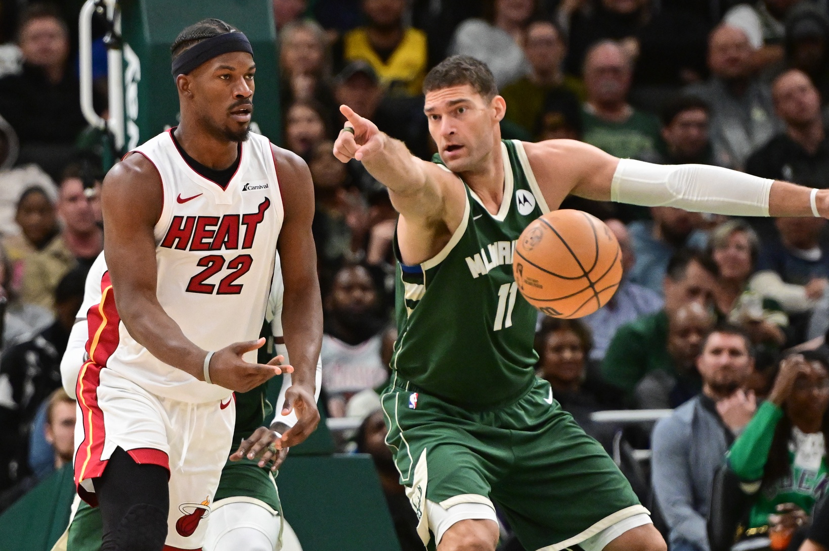 Oct 30, 2023; Milwaukee, Wisconsin, USA; Miami Heat center Jimmy Butler (22) passes the ball away from Milwaukee Bucks center Brook Lopez (11) in the second quarter at Fiserv Forum. Mandatory Credit: Benny Sieu-Imagn Images