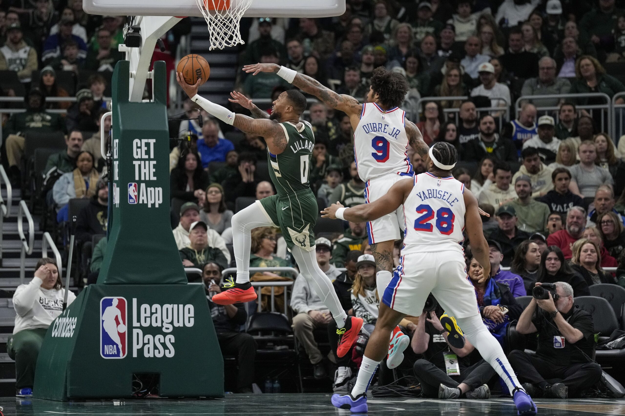 Feb 9, 2025; Milwaukee, Wisconsin, USA; Milwaukee Bucks guard Damian Lillard (0) shoots against Philadelphia 76ers forward Kelly Oubre Jr. (9) during the second quarter at Fiserv Forum. Mandatory Credit: Jeff Hanisch-Imagn Images